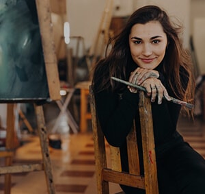 Une jeune femme artiste assise sur une chaise devant son tableau