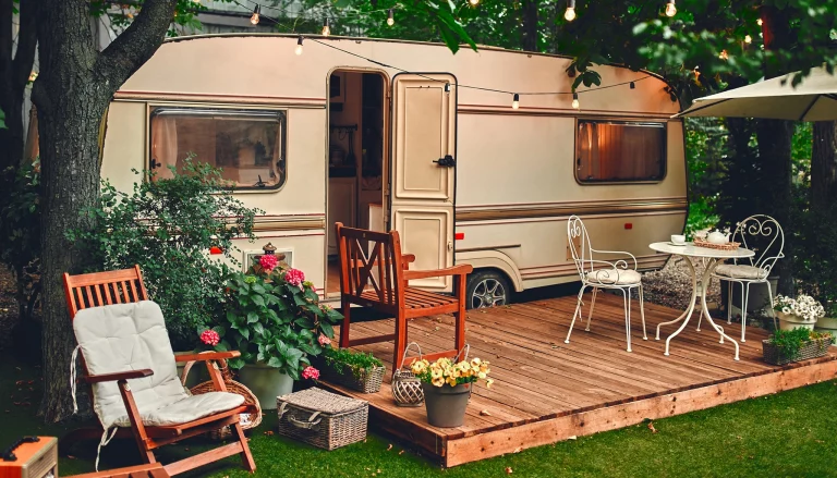 Ambiance chaleureuse et naturelle autour d'une caravane vintage, aménagée avec un espace extérieur cosy. Évasion et confort au cœur de la nature.