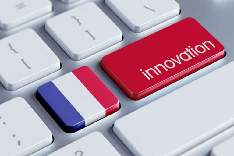 Photo en gros plan d'un clavier d'ordinateur avec deux touches colorées. La première touche, à gauche, est aux couleurs du drapeau français (bleu, blanc, rouge) et la seconde touche, à droite, est rouge avec le mot 'innovation' écrit en blanc. Les autres touches du clavier sont blanches avec des caractères standards.