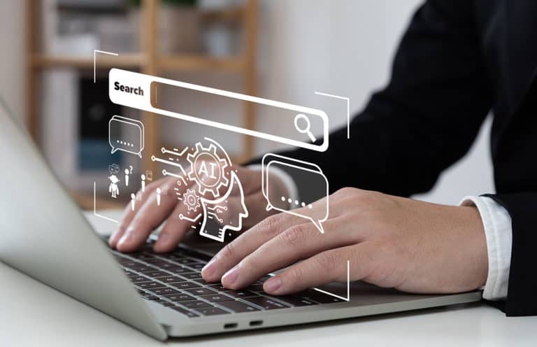 Personne utilisant un ordinateur portable avec une interface graphique superposée représentant une barre de recherche, des icônes de messagerie et des éléments liés à l'intelligence artificielle (IA). Les mains sont posées sur le clavier, illustrant l'interaction avec la technologie IA pour des recherches et des communications avancées. L'arrière-plan montre une étagère floue, ce qui met l'accent sur l'écran et les éléments graphiques.