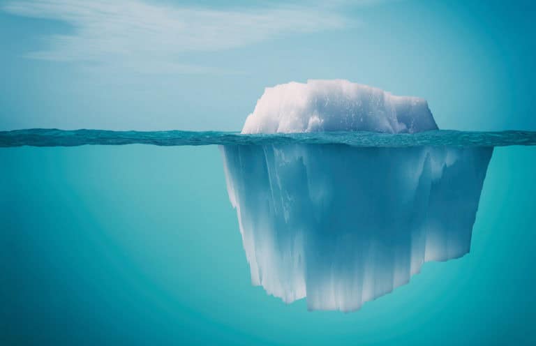 Image d'un iceberg dans une mer bleue claire, avec la partie visible au-dessus de l'eau et la partie immergée encore plus massive en dessous. Cette illustration est souvent utilisée pour symboliser la transparence, montrant que tout est visible et qu'il n'y a rien de caché sous la surface, représentant l'absence de frais cachés.